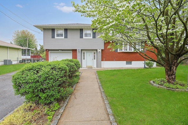 26 Hoke Dr, Stony Point, NY 10980 - split level home featuring central air condition unit, brick siding, an attached garage, and a front yard