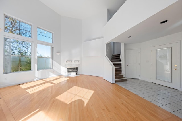 entryway featuring a high ceiling, stairs, baseboards, wood finished floors, and a high end fireplace