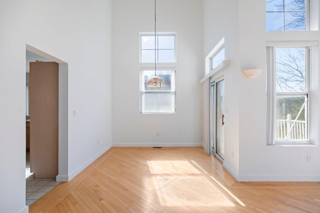 foyer featuring a high ceiling, baseboards, and light wood-type flooring