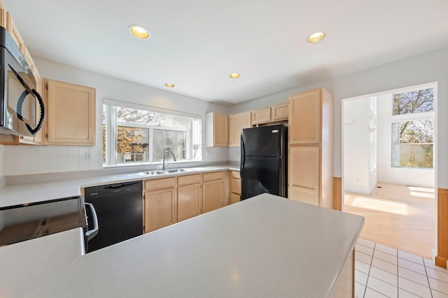 kitchen featuring light brown cabinetry, a healthy amount of sunlight, a sink, and black appliances