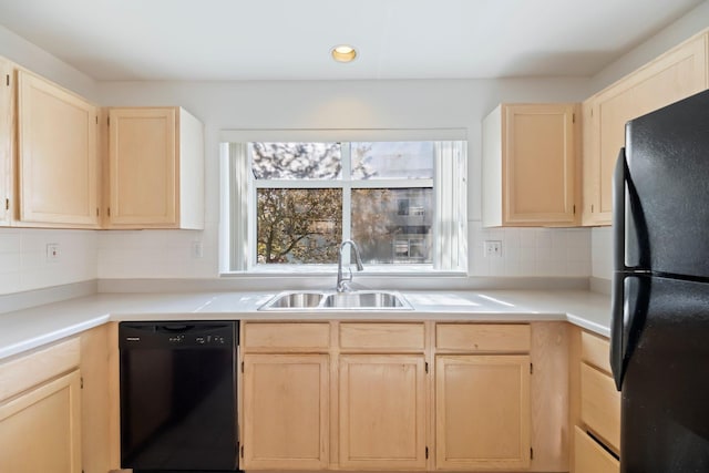 kitchen with a sink, black appliances, light brown cabinets, and tasteful backsplash