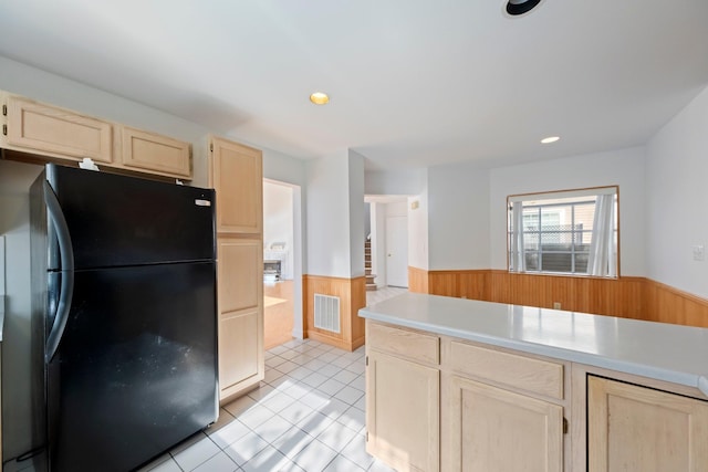 kitchen featuring light brown cabinetry, a wainscoted wall, freestanding refrigerator, and visible vents
