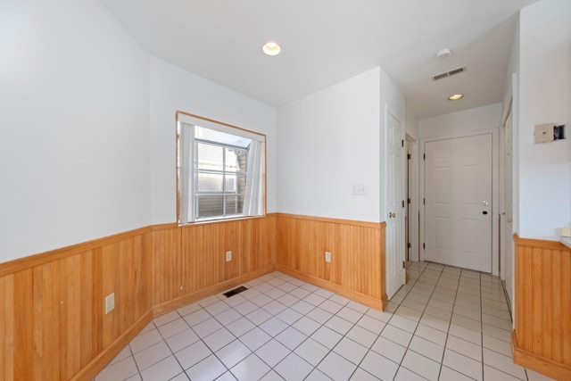 spare room with visible vents, wainscoting, and light tile patterned floors