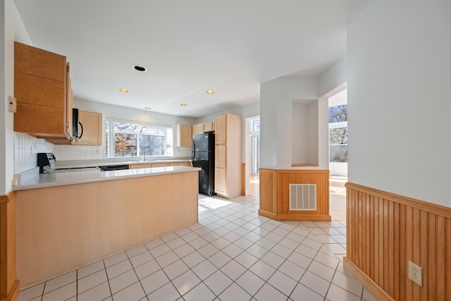 kitchen with visible vents, stove, wainscoting, a sink, and freestanding refrigerator