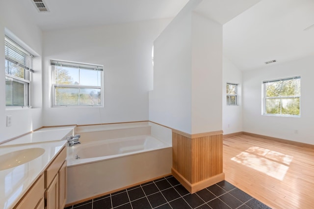 full bath featuring visible vents, lofted ceiling, a garden tub, and vanity