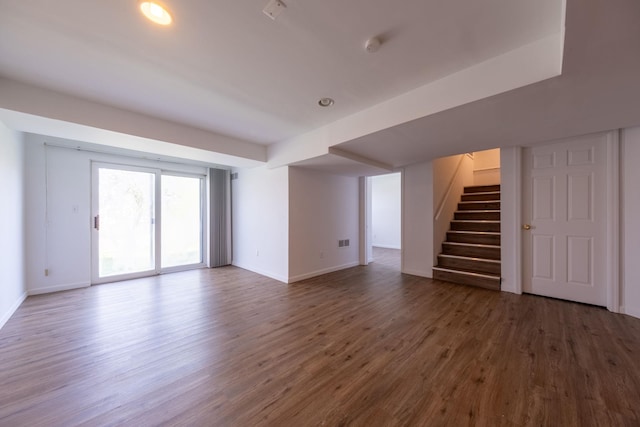 unfurnished living room featuring baseboards, wood finished floors, and stairway