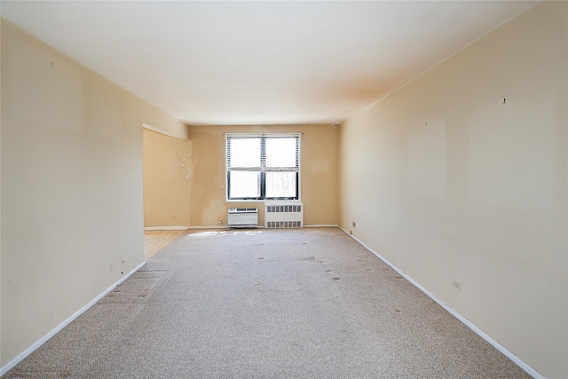 spare room with light colored carpet, baseboards, and an AC wall unit