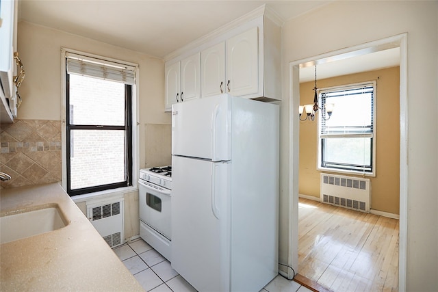 kitchen with a sink, radiator heating unit, a chandelier, and white appliances
