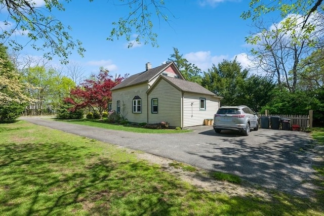 view of side of home with a yard, fence, and aphalt driveway
