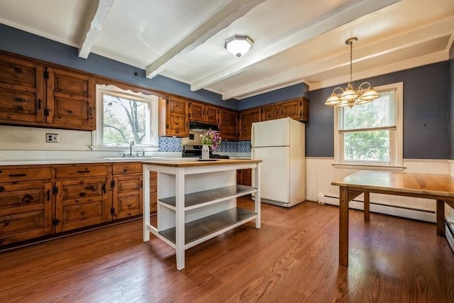 kitchen featuring freestanding refrigerator, beamed ceiling, light countertops, a wainscoted wall, and a chandelier