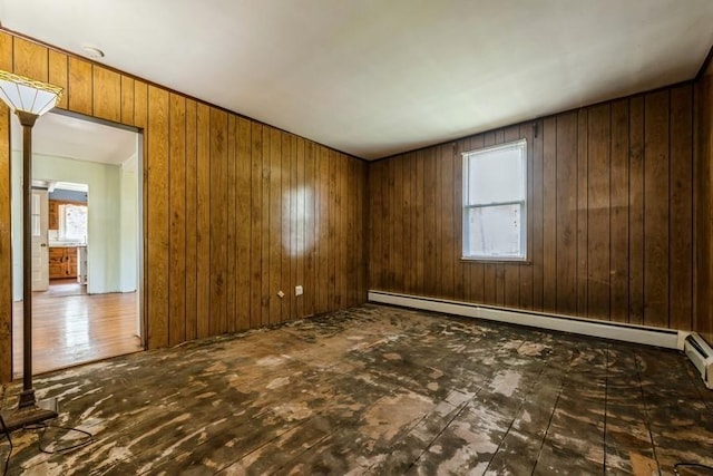 spare room featuring wooden walls and a baseboard radiator