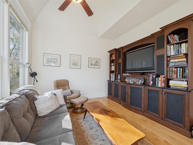living room featuring a ceiling fan, baseboards, light wood finished floors, and lofted ceiling