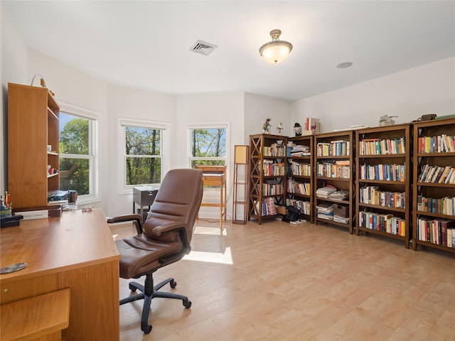 office area with light wood finished floors and visible vents