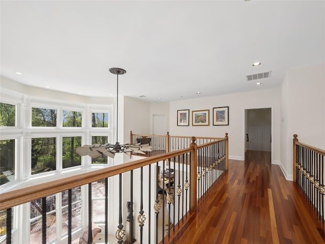 corridor featuring visible vents, wood finished floors, baseboards, recessed lighting, and an upstairs landing