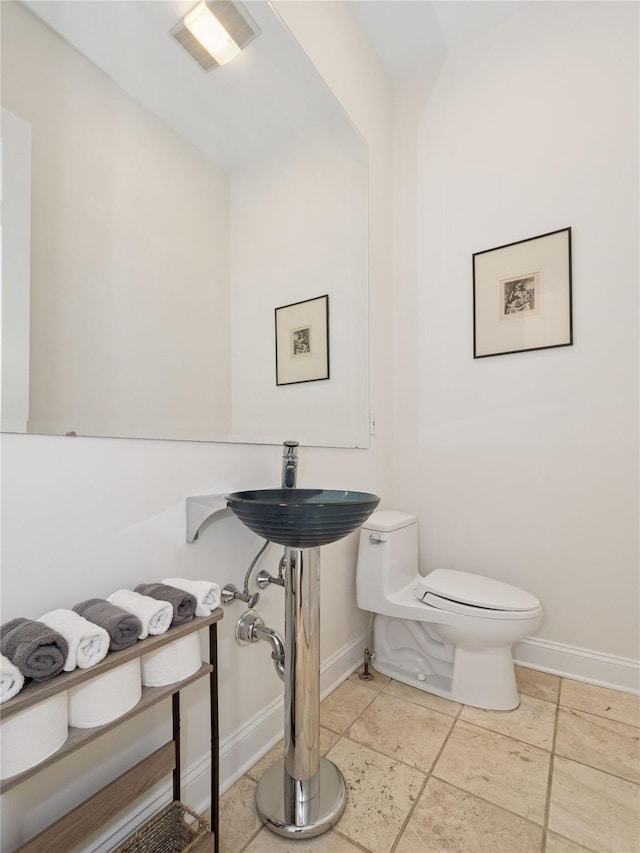 half bathroom with toilet, baseboards, and visible vents
