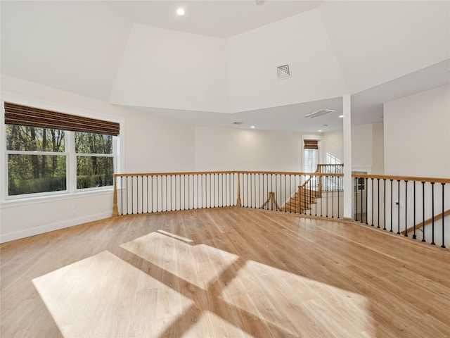 spare room with wood finished floors, recessed lighting, baseboards, and a high ceiling