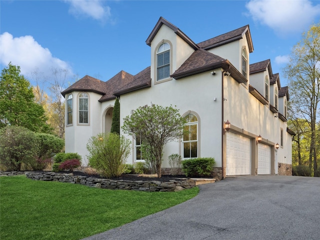 view of front of home with stone siding, aphalt driveway, a front yard, and stucco siding