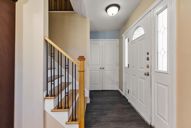 entryway with a textured ceiling, dark wood-style floors, baseboards, and stairway