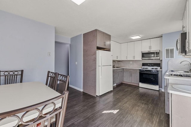 kitchen with gas stove, a sink, freestanding refrigerator, stainless steel microwave, and visible vents