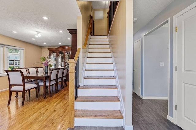 stairway featuring baseboards, recessed lighting, a textured ceiling, and wood finished floors