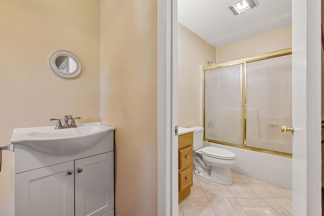 bathroom featuring tile patterned flooring, vanity, toilet, combined bath / shower with glass door, and visible vents