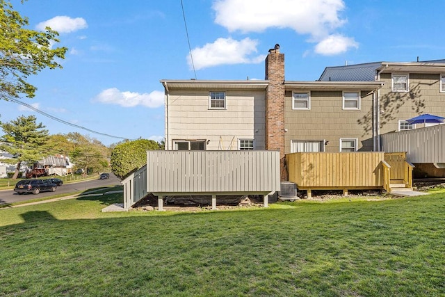 back of house with a chimney, a yard, central AC, and a deck