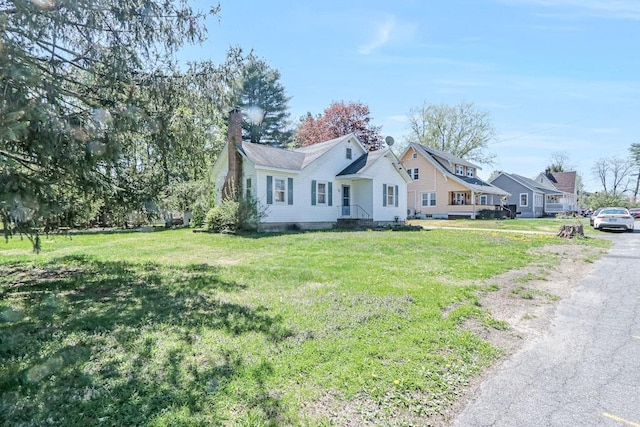 view of front of house with a chimney and a front lawn