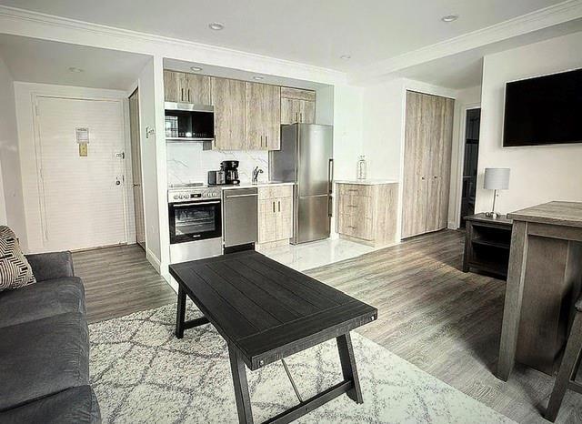 kitchen featuring backsplash, light countertops, light wood-style floors, ornamental molding, and stainless steel appliances