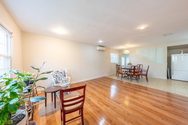 dining area featuring an AC wall unit, baseboards, visible vents, and light wood-style flooring