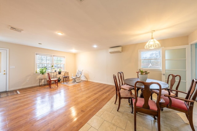 dining room featuring visible vents, baseboards, an AC wall unit, recessed lighting, and light wood-style flooring