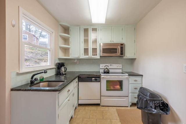 kitchen featuring white appliances, decorative backsplash, a sink, and a healthy amount of sunlight
