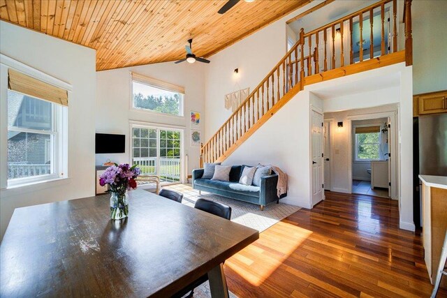 dining room featuring high vaulted ceiling, a ceiling fan, wooden ceiling, wood finished floors, and stairway