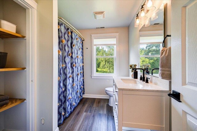 full bath featuring visible vents, wood finished floors, vanity, baseboards, and toilet