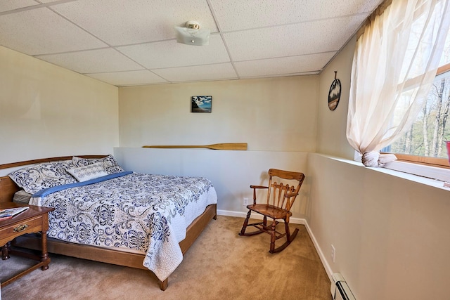 carpeted bedroom featuring baseboards and a drop ceiling