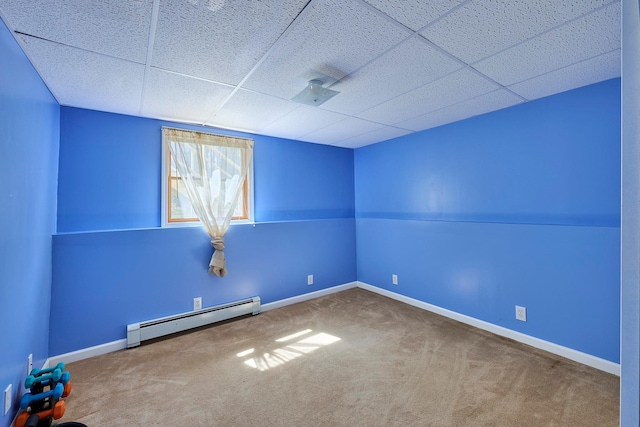 unfurnished room with baseboards, a baseboard radiator, carpet flooring, and a drop ceiling