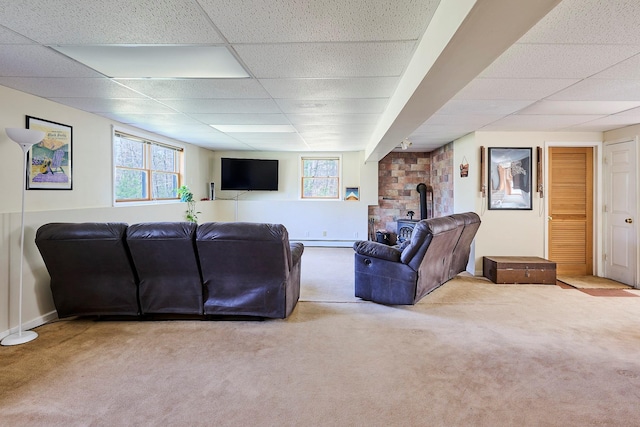 living room with carpet floors, a drop ceiling, and a wood stove