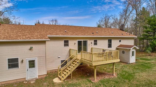 back of house featuring an outdoor structure, a wooden deck, a shed, a lawn, and stairway