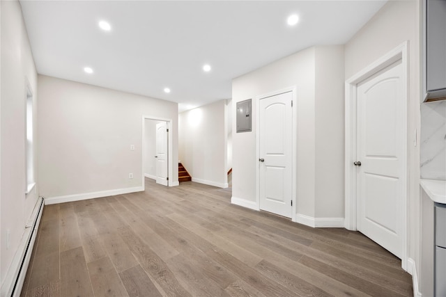 61-12 160th St, Fresh Meadows, NY 11365 - below grade area with a baseboard heating unit, light wood-style flooring, electric panel, recessed lighting, and stairway
