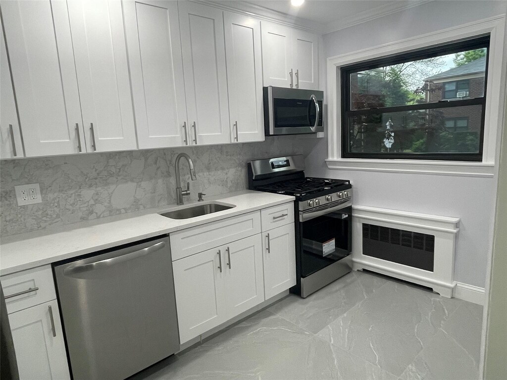 22048 75th Ave Unit A1, Bayside, NY 11364 - kitchen with appliances with stainless steel finishes, a sink, light marble finish flooring, crown molding, and decorative backsplash
