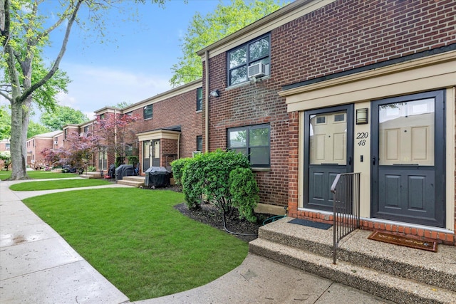 22048 75th Ave Unit A1, Bayside, NY 11364 - view of exterior entry featuring brick siding, a yard, and cooling unit