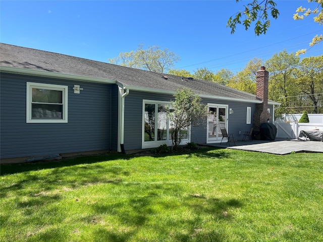 back of house featuring a lawn and a shingled roof