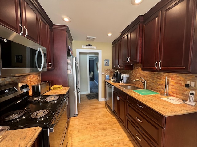 kitchen featuring light wood-style floors, decorative backsplash, appliances with stainless steel finishes, and visible vents