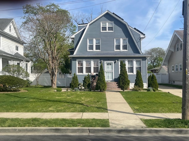 colonial inspired home featuring fence, a front lawn, and a gambrel roof