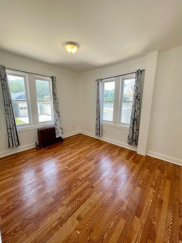 58 7th St, Valley Stream, NY 11581 - empty room with radiator heating unit, wood finished floors, and healthy amount of natural light