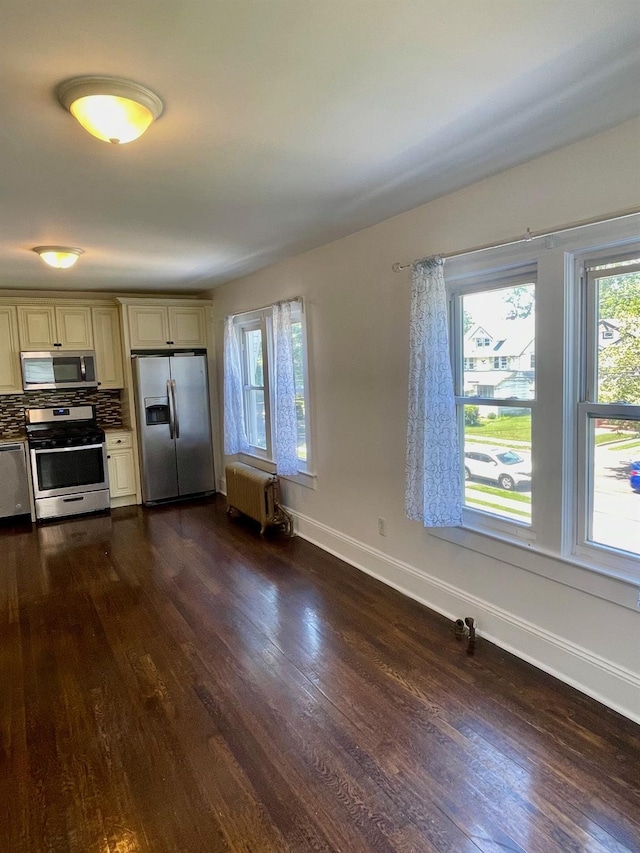 58 7th St, Valley Stream, NY 11581 - kitchen featuring stainless steel appliances, cream cabinets, radiator heating unit, dark wood-style flooring, and tasteful backsplash