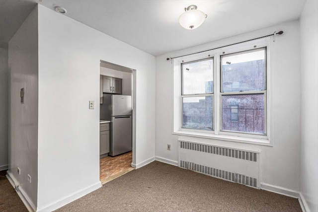 unfurnished dining area featuring plenty of natural light, baseboards, carpet floors, and radiator heating unit