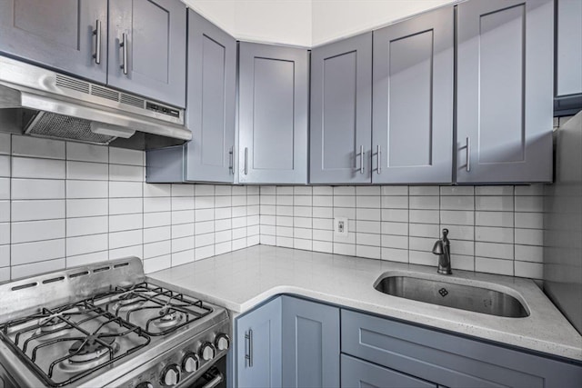 kitchen with a sink, decorative backsplash, stainless steel gas range oven, and under cabinet range hood