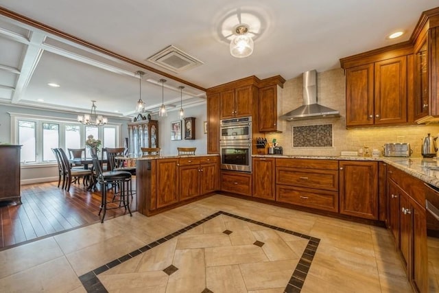 708 Seabury Ave, Franklin Square, NY 11010 - kitchen featuring stainless steel double oven, a peninsula, an inviting chandelier, a breakfast bar, and wall chimney exhaust hood