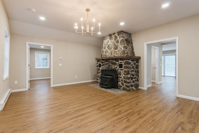 435 State Route 55, Eldred, NY 12732 - unfurnished living room featuring a wood stove, wood finished floors, a chandelier, and a healthy amount of sunlight