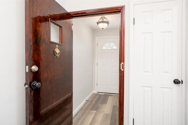 doorway with baseboards and light wood-type flooring